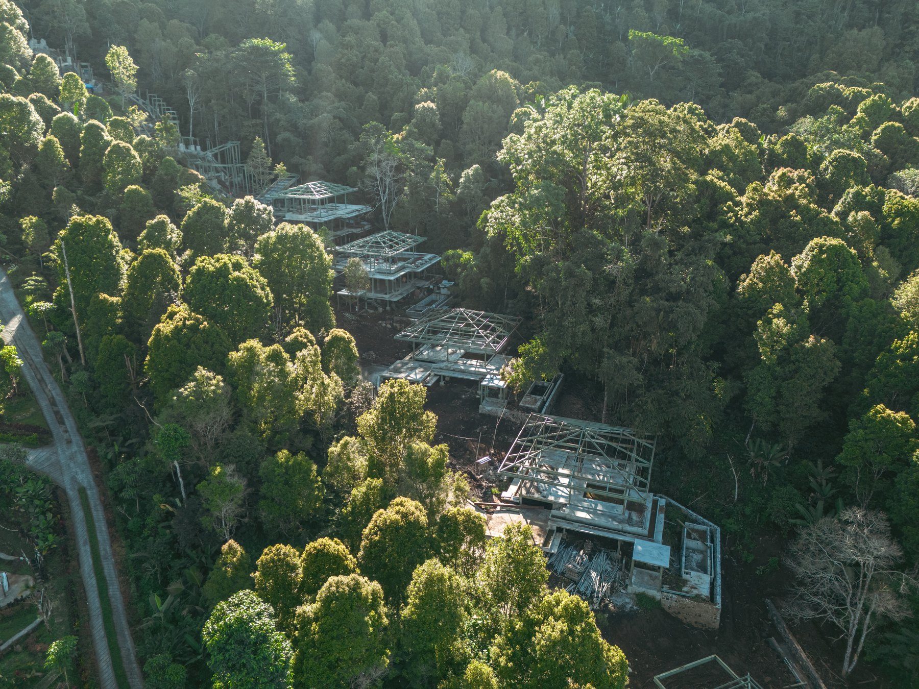 Golden-hour aerial of the eight villas set into the Munduk forest